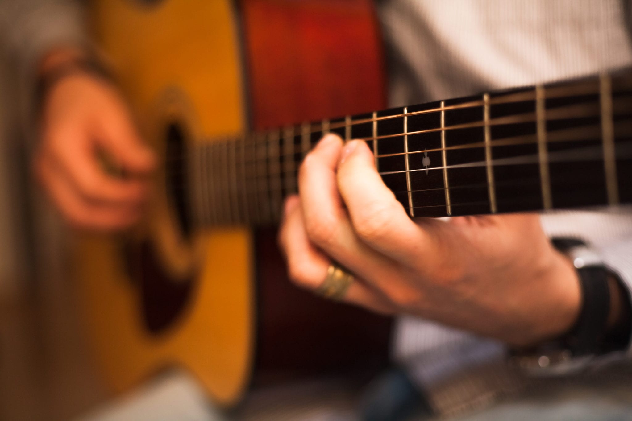 Closeup of a music therapist's hands on a guitar.