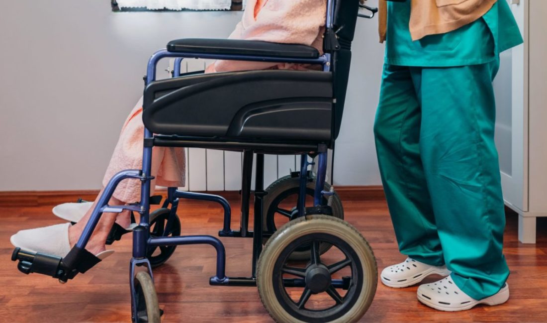 A registered nurse moves a hospice patient in a wheelchair.