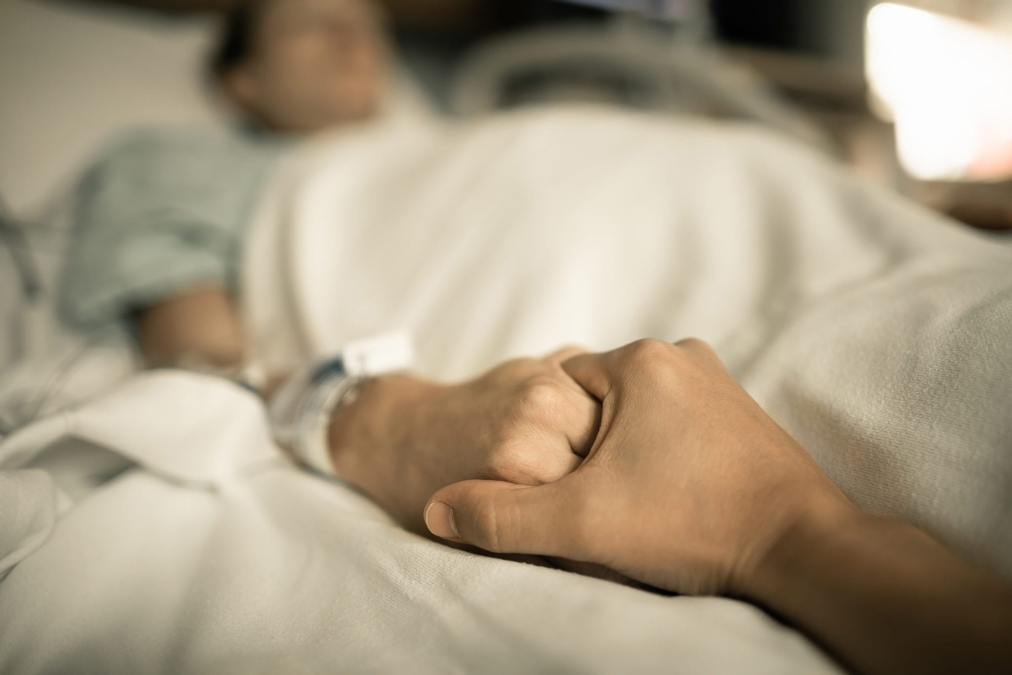 Man holding woman hand in hospital bed. Holding hands in hospital bed.